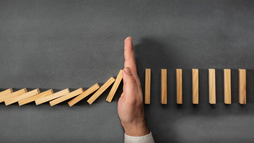 Hand houdt omvallende dominostenen tegen Hand houdt omvallende dominostenen tegen