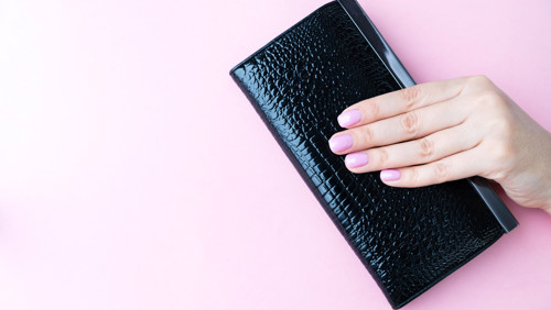 Hand met roze nagellak houdt portemonnee vast Hand met roze nagellak houdt portemonnee vast