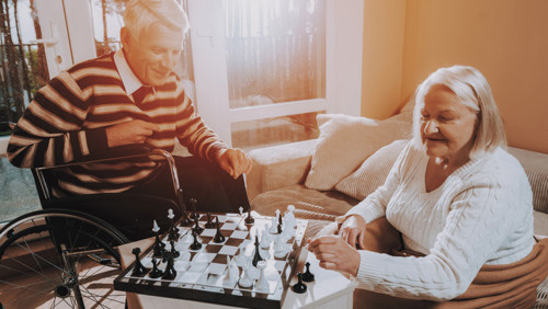 Man in rolstoel en vrouwelijke mantelzorger schaken Man in rolstoel en vrouwelijke mantelzorger schaken