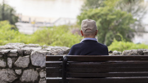 Man zit buiten op bankje en geniet van uitzicht Man zit buiten op bankje en geniet van uitzicht