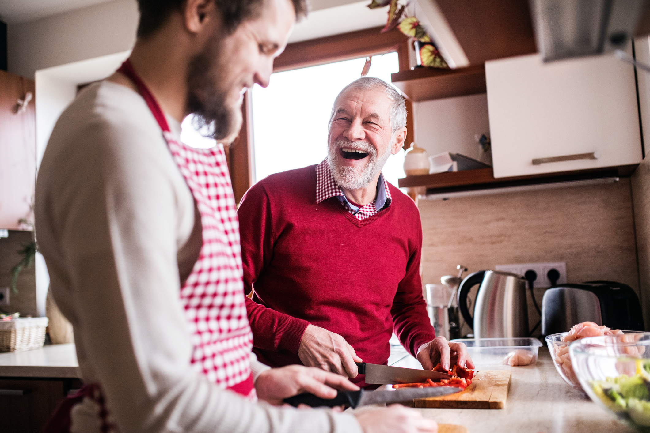 Jonge mantelzorger en vader in rode trui koken en genieten van sociale leven