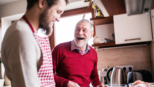Jonge mantelzorger en vader in rode trui koken en genieten van sociale leven Jonge mantelzorger en vader in rode trui koken en genieten van sociale leven