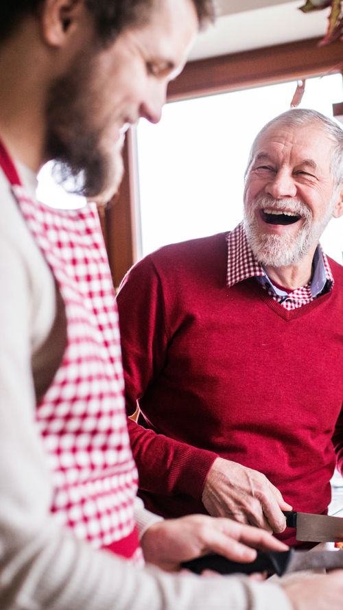 Jonge mantelzorger en vader in rode trui koken en genieten van sociale leven Jonge mantelzorger en vader in rode trui koken en genieten van sociale leven