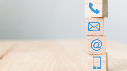 Tafel met blokken met daarop iconen van telefoon en mail Tafel met blokken met daarop iconen van telefoon en mail