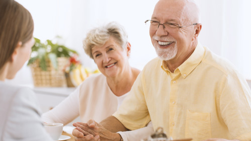 Lachend echtpaar in gesprek met vrouw over keukentafelgesprek Lachend echtpaar in gesprek met vrouw over keukentafelgesprek