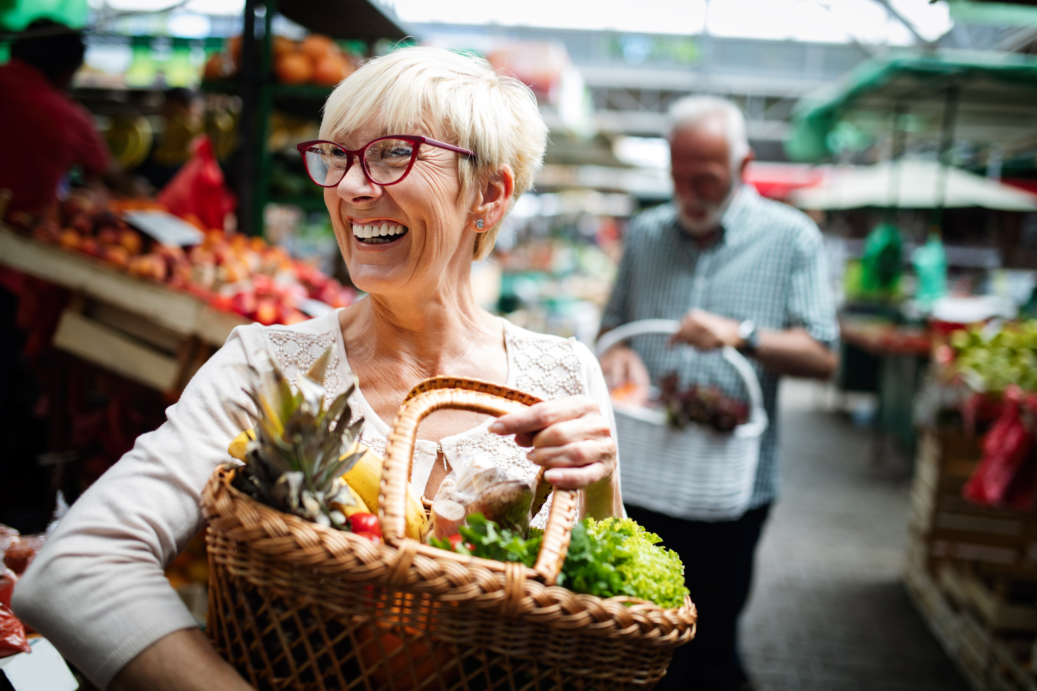 Lachende vrouw op de markt met mand vol gezond eten