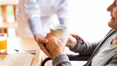 Oude vrouw krijgt koffie van professionele hulp in huis Oude vrouw krijgt koffie van professionele hulp in huis