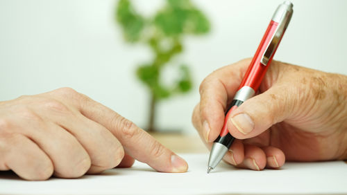 Iemand wijst op het papier waar de ander met de pen de gegevens kan invullen Iemand wijst op het papier waar de ander met de pen de gegevens kan invullen