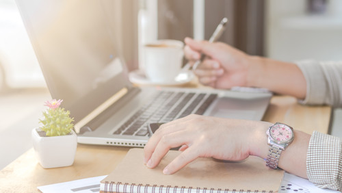 Mevrouw zit achter laptop met notitieboek erbij en ontdekt hoe een indicatie aanvragen Mevrouw zit achter laptop met notitieboek erbij en ontdekt hoe een indicatie aanvragen