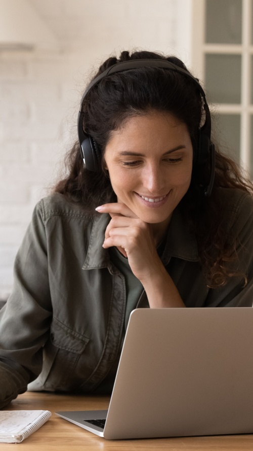 Vrouw volgt een online webinar aan de keukentafel Vrouw volgt een online webinar aan de keukentafel
