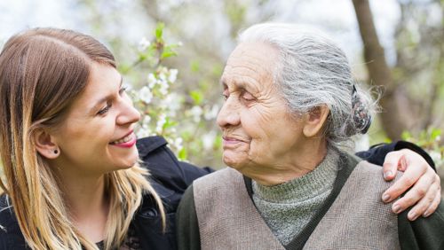 Jonge vrouw en oude vrouw glimlachen naar elkaar Jonge vrouw en oude vrouw glimlachen naar elkaar