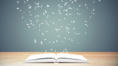 Boek op tafel met zwevende letters erboven Boek op tafel met zwevende letters erboven