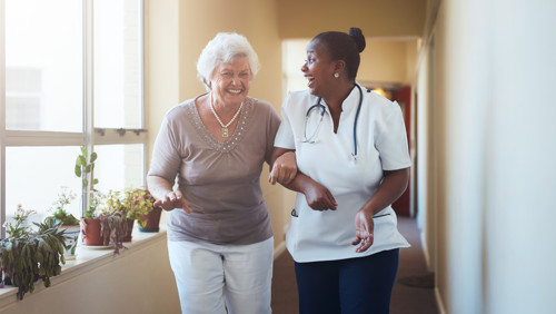 Vrouw lacht naar oude vroeg in ziekenhuisgang Vrouw lacht naar oude vroeg in ziekenhuisgang