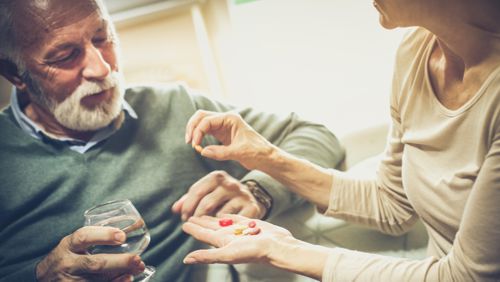 Mantelzorger geeft man medicijnen Mantelzorger geeft man medicijnen