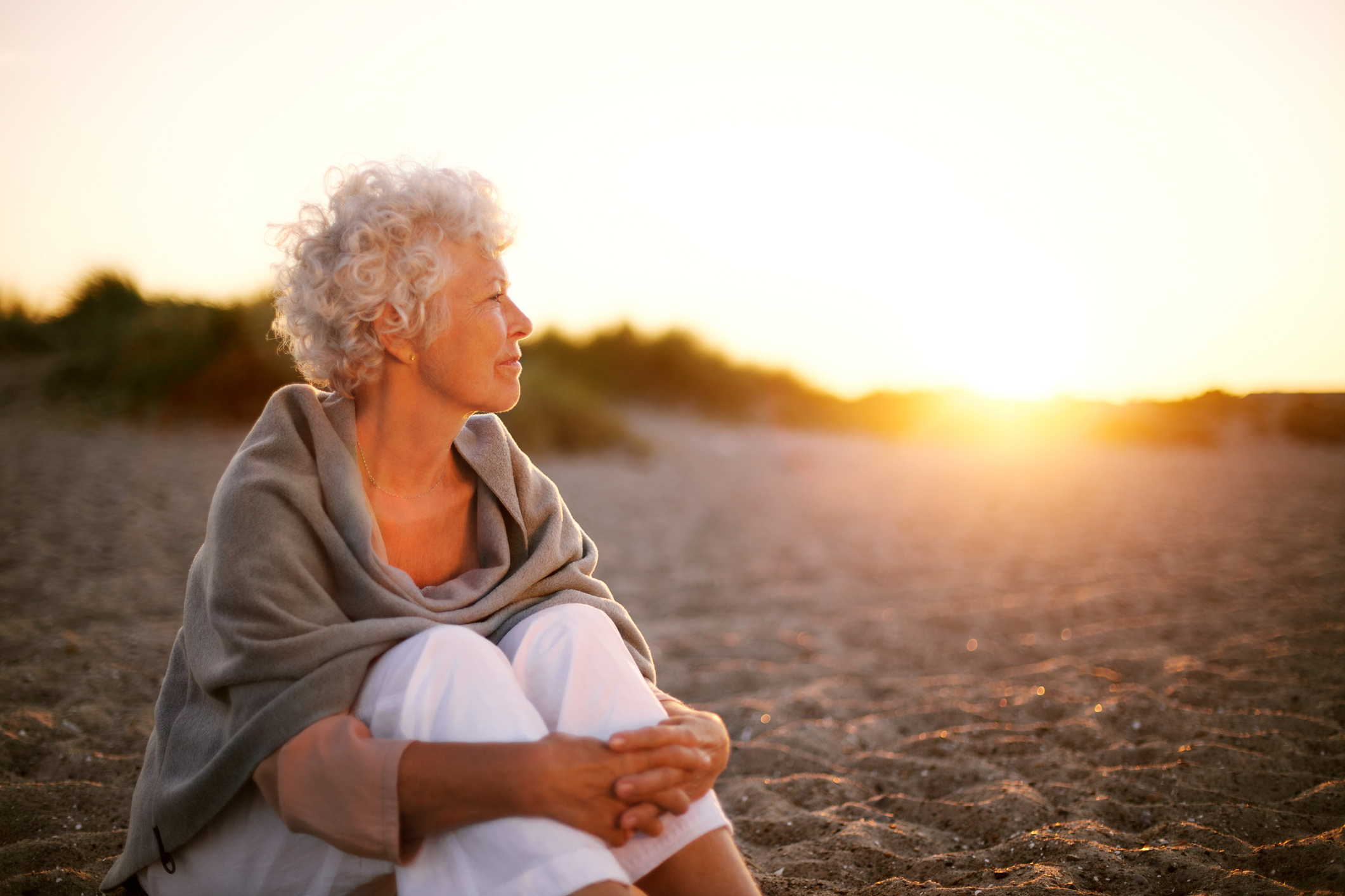 Vrouwelijke mantelzorger geniet van haar vrije tijd op het strand bij zonsondergang