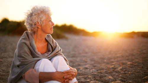 Vrouwelijke mantelzorger geniet van haar vrije tijd op het strand bij zonsondergang Vrouwelijke mantelzorger geniet van haar vrije tijd op het strand bij zonsondergang